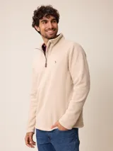 Sweater de polar color beige, con cuello alto y cierre frontal parcial. Presenta un pequeño logo bordado en el pecho.