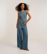 Pantalón de jeans de tiro alto, corte ancho (wide leg/pantalona) en tono celeste desgastado. Presenta cierre y botones frontales, trabillas en la cintura y bolsillos delanteros y traseros.