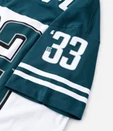 Remera de corte oversized con diseño deportivo de los Philadelphia Eagles. Presenta cuello redondo, mangas cortas con detalles de rayas y estampa frontal del equipo. Confeccionada en algodón.