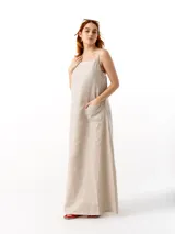 Vestido largo de lino color beige, con breteles finos regulables, escote recto, bolsillos laterales y tajo lateral.