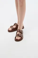Sandalias planas de mujer con doble tira ancha en el empeine, hebillas metálicas plateadas y textura símil cocodrilo.
