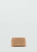 Bolso tipo bandolera de tamaño mini, confeccionado en fibras naturales tejidas con diseño de espiga. Presenta cierre de solapa con botón magnético, detalles de tachas metálicas en los bordes, forro interior y asa larga de cadena metálica dorada.