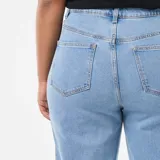 Jean de corte bootcut con cintura alta y cierre frontal con botón y cremallera. Presenta un diseño de cinco bolsillos y un acabado deshilachado en el bajo.