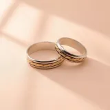 Par de alianzas de boda combinadas en plata y oro de 9k, con un diseño central trenzado.