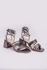 Sandalias doradas con taco cuadrado y tiras finas que se atan al tobillo. Capellada, forro y plantilla 100% de cuero.