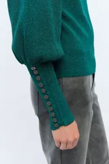 Sweater color crema de tejido de punto con lurex, mangas abullonadas y puños con botones metálicos.