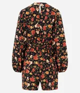 Enterito corto de viscosa con estampado floral sobre fondo negro, escote en V, mangas largas con volumen y puños ajustados.