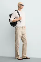 Mochila de diseño minimalista en color negro con acabado texturizado. Cuenta con un compartimento principal con cierre de cremallera, un bolsillo frontal con solapa y compartimento interior para dispositivos electrónicos. Incluye espalda acolchada, banda de sujeción para equipaje, asa de mano y correas de hombro ajustables.