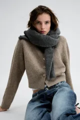 Chaqueta de punto suave en color beige melange, con cuello redondo, manga larga y cierre frontal de botones.