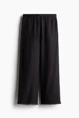 Pantalón de corte holgado en tejido liviano de mezcla de lino y viscosa, color negro, con cintura elástica fruncida, cordón ajustable, bolsillos laterales y piernas rectas con bajo deshilachado.