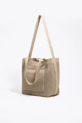 Bolso shopper mediano de tejido de punto color beige, con doble asa corta de mano y una correa larga ajustable para el hombro. Incluye parche con logo en la parte frontal.