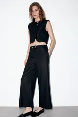 Chaleco color beige con cuello redondo, manga sisa y cierre frontal cruzado con dos botones dorados. Cuenta con falsos bolsillos con solapa en el frente.