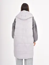 Chaleco largo acolchado con capucha, diseño matelaseado horizontal y cierre frontal oculto.