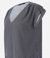 Blusa de crepé con estampado geométrico en blanco y negro, escote en V y mangas cortas sin sisa con detalle fruncido en los hombros.