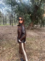 Campera de cuero con efecto envejecido en tonos marrones, de calce relajado y estructurado, con cuello alto y cierre frontal.