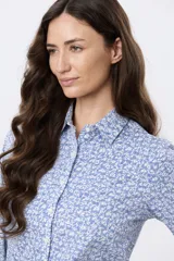 Camisa de manga larga con estampado floral en tonos azules y blancos, cuello camisero y cierre frontal de botones.