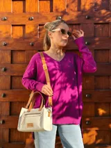 Cartera bandolera de cuero crudo con forro de tela, bolsillo frontal y bolsillo interno. Tiene correa larga regulable y manijas cortas de cuero marrón.