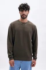 Buzo de tejido de punto color marrón oscuro, con cuello redondo y manga larga. Presenta una textura acanalada vertical.