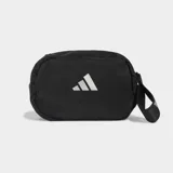 Bolso deportivo pequeño tipo pouch de color negro, con forma ovalada y logo Badge of Sport de Adidas reflectante en el centro. Cuenta con correa ajustable y removible.