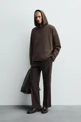 Sudadera tipo hoodie de corte relajado, confeccionada en tejido de algodón con interior de rizo. Presenta cuello con capucha, manga larga y acabados con bordes enrollados.
