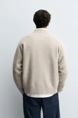 Chaqueta tipo bomber de punto en hilatura de lana, con cuello subido, manga larga, bolsillos de vivo en la cadera, acabados en rib y cierre frontal de cremallera.