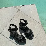 Sandalias de plataforma tipo cuña, color marrón, con tiras de cuero texturizado y costuras decorativas. Cuentan con tira al tobillo con hebilla metálica y plataforma corrida.