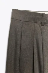 Pantalón de tiro alto con pierna ancha, confeccionado con detalle de pinzas en el delantero, bolsillos laterales y cierre frontal con cremallera y gancho metálico.