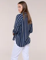 Camisa de crepe blanca con rayas verticales negras, cuello camisero, mangas largas raglán y cierre frontal con botones.