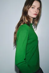 Jersey de punto liso color verde, con cuello redondo y manga larga. Confeccionado en lana suave.