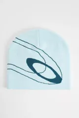 Gorro tipo beanie de punto fino color celeste, con diseño jacquard del logotipo Ellipse de Oakley en color azul oscuro. Modelo reversible de silueta sencilla.