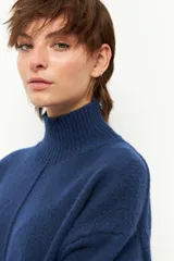 Polera de tejido de punto color azul, con cuello alto acanalado, manga larga y costura vertical central en el frente.