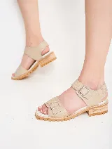 Sandalias de cuero color ocre con doble tira sobre el empeine y hebillas metálicas plateadas. Suela de goma con plataforma baja y detalle de costuras.