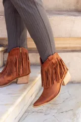 Bota texana de caña corta color marrón, fabricada en cuero con forro de cuero. Presenta cierre lateral y flecos en el tobillo.