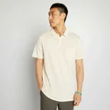 Remera tipo polo color crema, de piqué de algodón, con cuello clásico, tapeta de dos botones y bolsillo de parche en el pecho.