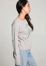 Camiseta gris de manga larga con cuello redondo y estampado frontal con la frase "J'ADORE Paris 72" en color verde.