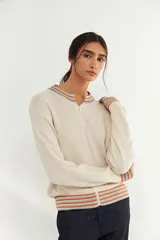 Bomber de tejido de punto color crudo, con cierre frontal completo y detalles de franjas multicolores en cuello, puños y ruedo.