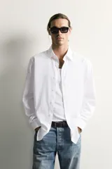 Camisa slim fit de Zara confeccionada en tejido de algodón con textura estructurada, cuello clásico con solapa y manga larga con puños abotonados. Cierre frontal con botonadura.