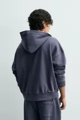 Sudadera de algodón con efecto lavado, color azul oscuro/gris pizarra, de corte 'boxy fit' y cierre frontal de cremallera. El interior de la capucha está forrado en tejido waffle de color gris claro. Posee bolsillos frontales de plastrón.