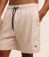 Bermuda de baño color beige, con cintura elástica y cordón de ajuste negro. Presenta un pequeño parche gomoso en el ruedo y bolsillos laterales.