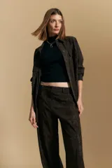 Pantalón de corte ancho y silueta relajada, confeccionado en tejido de efecto gamuzado color marrón oscuro. Presenta un diseño de tiro alto con cierre frontal y bolsillos laterales.