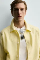 Sobrecamisa relaxed fit de color amarillo claro, confeccionada en tejido con mezcla de lyocell. Presenta cuello solapa, mangas largas raglán con puños abotonados, bolsillos de vivo en la cadera y cierre frontal con botonadura.
