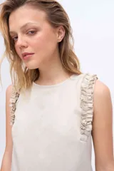 Musculosa negra con cuello redondo y detalles de volados en los hombros, confeccionada en una mezcla de algodón y Tencel.