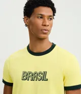 Remera de algodón color amarillo con cuello redondo y bordes de mangas en color verde oscuro. Presenta estampado frontal con la palabra Brasil en tipografía estilo retro.