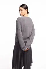 Buzo de punto inglés grueso en color gris melange, de corte amplio con hombros caídos y mangas largas, con sutil bordado de la marca en el pecho.