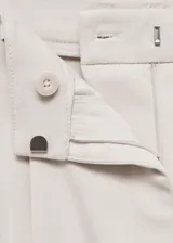 Pantalon de vestir color beige, de corte recto y tiro medio. Presenta detalle de pinzas en la parte frontal, bolsillos laterales y cierre oculto con botón, gancho y cremallera.