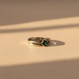 Anillo de plata con diseño de doble banda y piedra central de circonia en color verde.