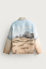 Cazadora relaxed fit de tejido jacquard ligeramente acolchado, con estampado de paisaje costero y texto "Un dernier souffle d'été". Cuenta con cuello solapa con inscripción, manga larga, bolsillos de vivo en la cadera y cierre frontal con cremallera.