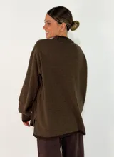 Sweater de tejido de punto en color azul marino, con cuello redondo, mangas largas con puños acanalados y ajuste holgado. Presenta un pequeño aplique decorativo en el ruedo.