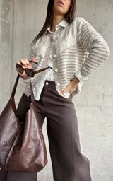 Cardigan de punto con diseño de rayas horizontales en tonos beige y blanco, cuello redondo y cierre frontal con botones. Presenta mangas largas con puños ajustados.