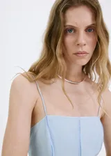 Vestido midi celeste de tirantes finos, con escote cuadrado y costuras verticales decorativas. Confeccionado en mezcla de lyocell y poliamida, con forro interior de algodón.